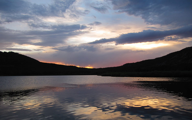 A lake landscape surrounded by hills in a sunset atmosphere (Karkaralinsky region in Kasachstan).