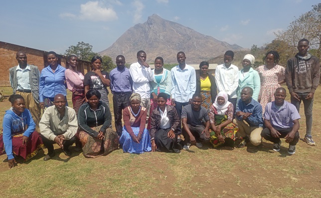 Group photo of participants with bare forest reserve in the background